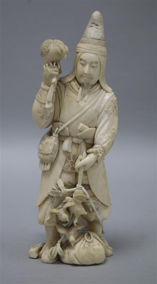 A Japanese carved ivory okimono of a huntsman, Meiji period, holding a hawk and a brace of birds